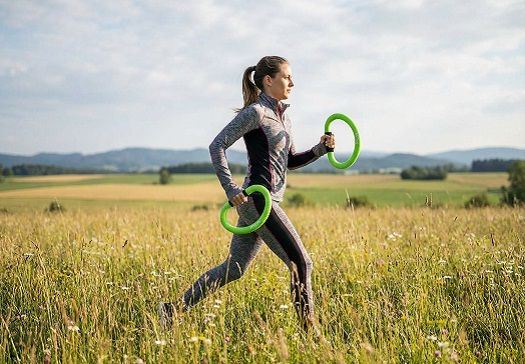 Junge Frau in Sportkleidung joggt mit grünen Ringen.