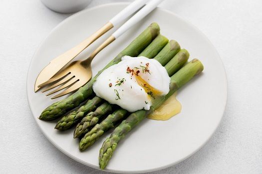 Teller mit Spargeln, Ei und Besteck