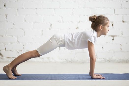 Das M&auml;dchen macht eine Yoga-Pose auf der Matte.