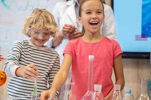 Fr&ouml;hliche Kinder machen Experimente mit Wasser.