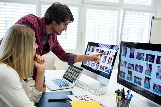 Zwei Grafikdesigner schauen sich Fotos auf dem Computer an.