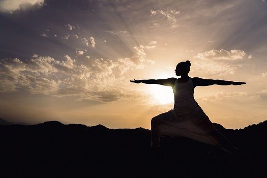 Silhouette der Person, die in der Sonne eine meditative Übung macht.