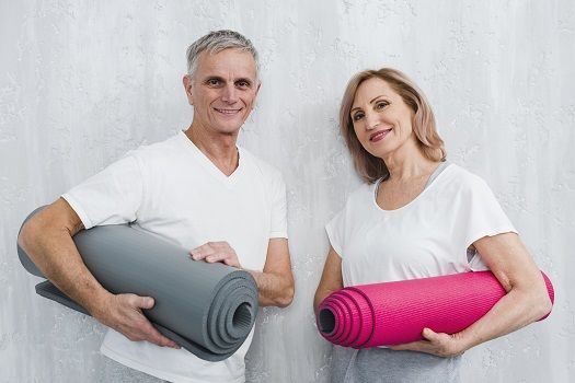 Ein älteres Paar posiert mit Gymnastikmatten.