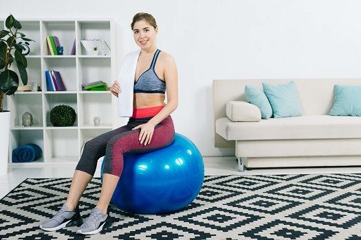 Junge Frau sitzt auf einem Pilates-Ball.