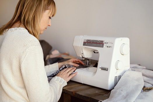 Frau sitzt an einer N&auml;hmaschine in einem Atelier.