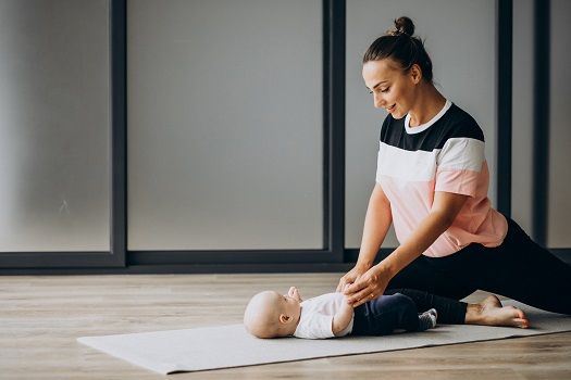 Mama mit Baby sitzt auf einer Matte.