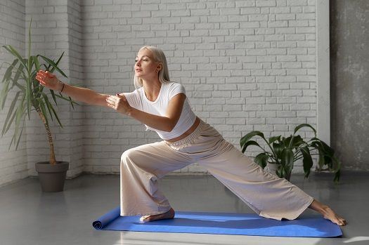 Blonde Frau macht eine Qigong-Übung auf der Matte.