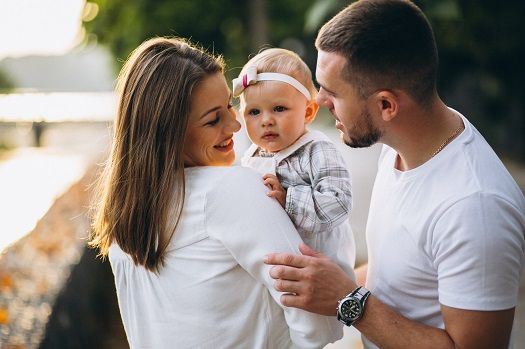 Eltern posieren mit ihrem Baby zum Foto.